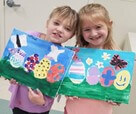 two children holding up their easter paintings