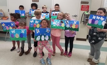 a group of children holding up their artwork of easter eggs