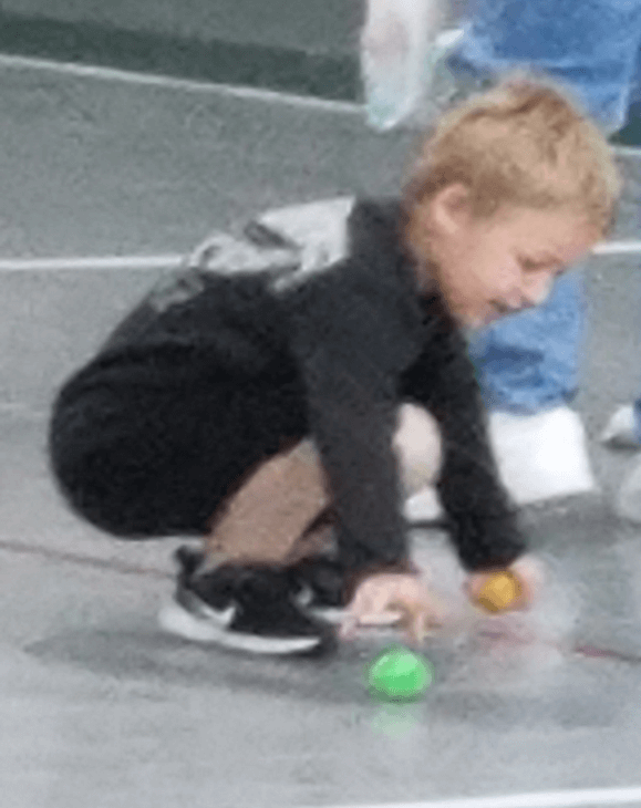 a little boy squatting down to pick up an egg
