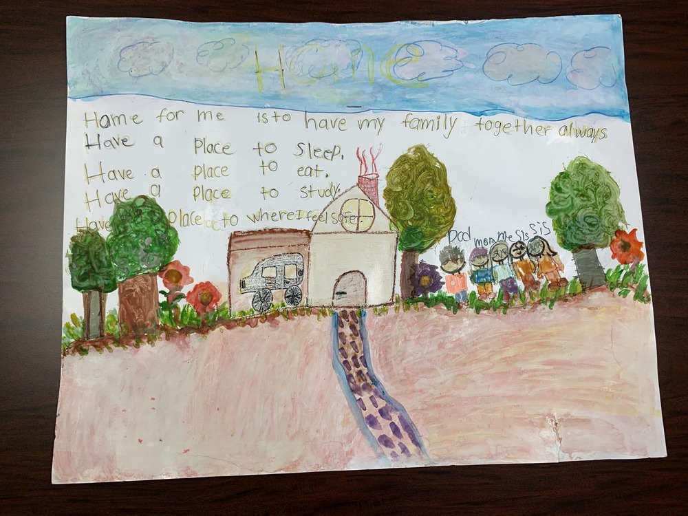 What Home Means to Me Poster Contest, September 2022 Winner. Poster features a home with an attached garage and the family is standing outside under a sunny sky. 