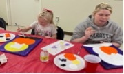 Two girls are sitting at a table and painting.
