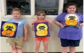 3 children stand together and show off their cat paintings.