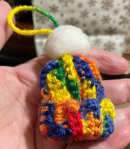 A tiny colorful winter hat rest in someones hand. 