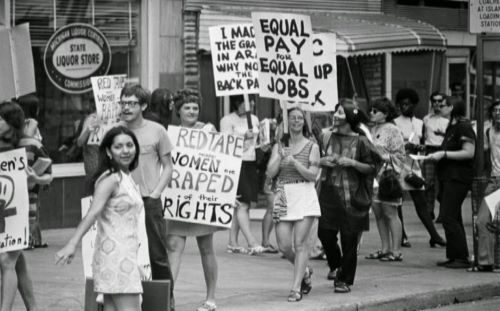 A large crowd of women holding picket signs with equal rights slogans.